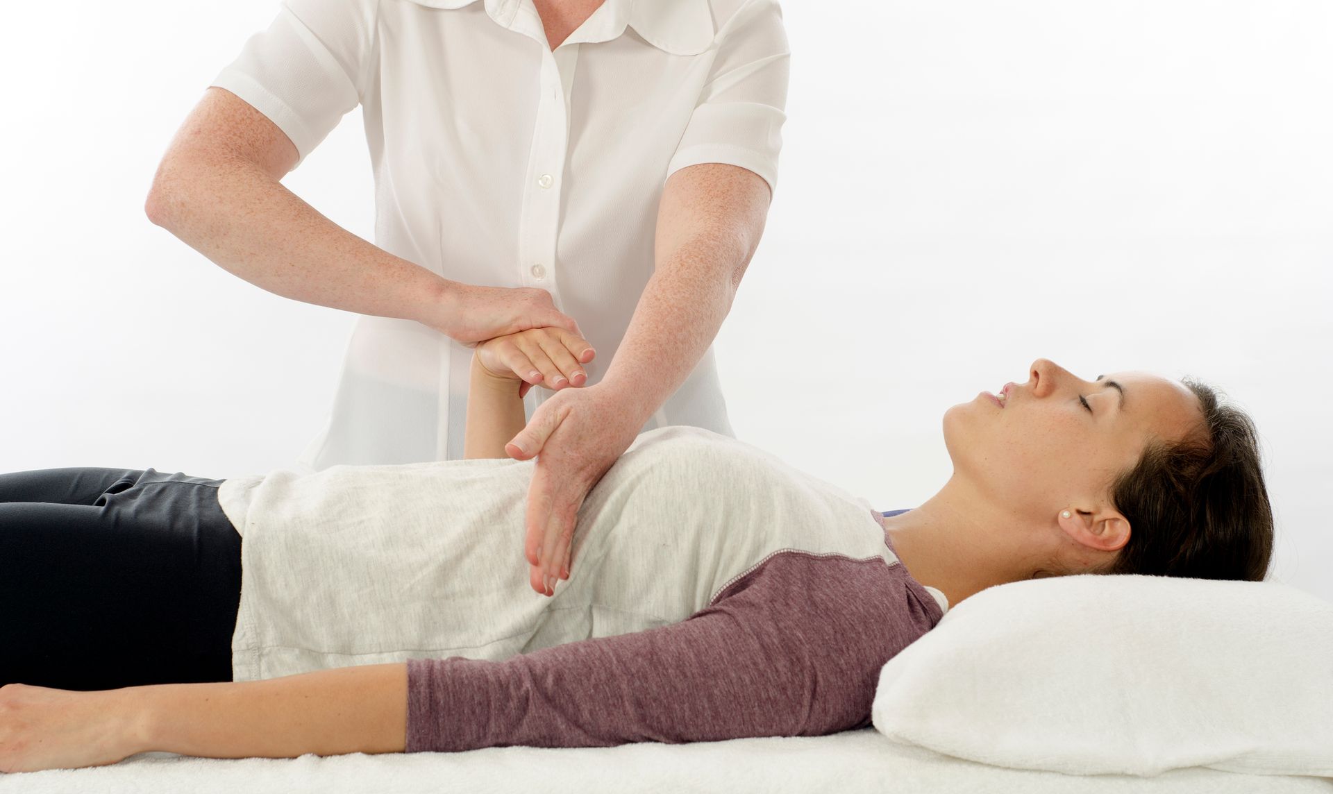 A woman is laying on a bed getting a massage from a doctor.