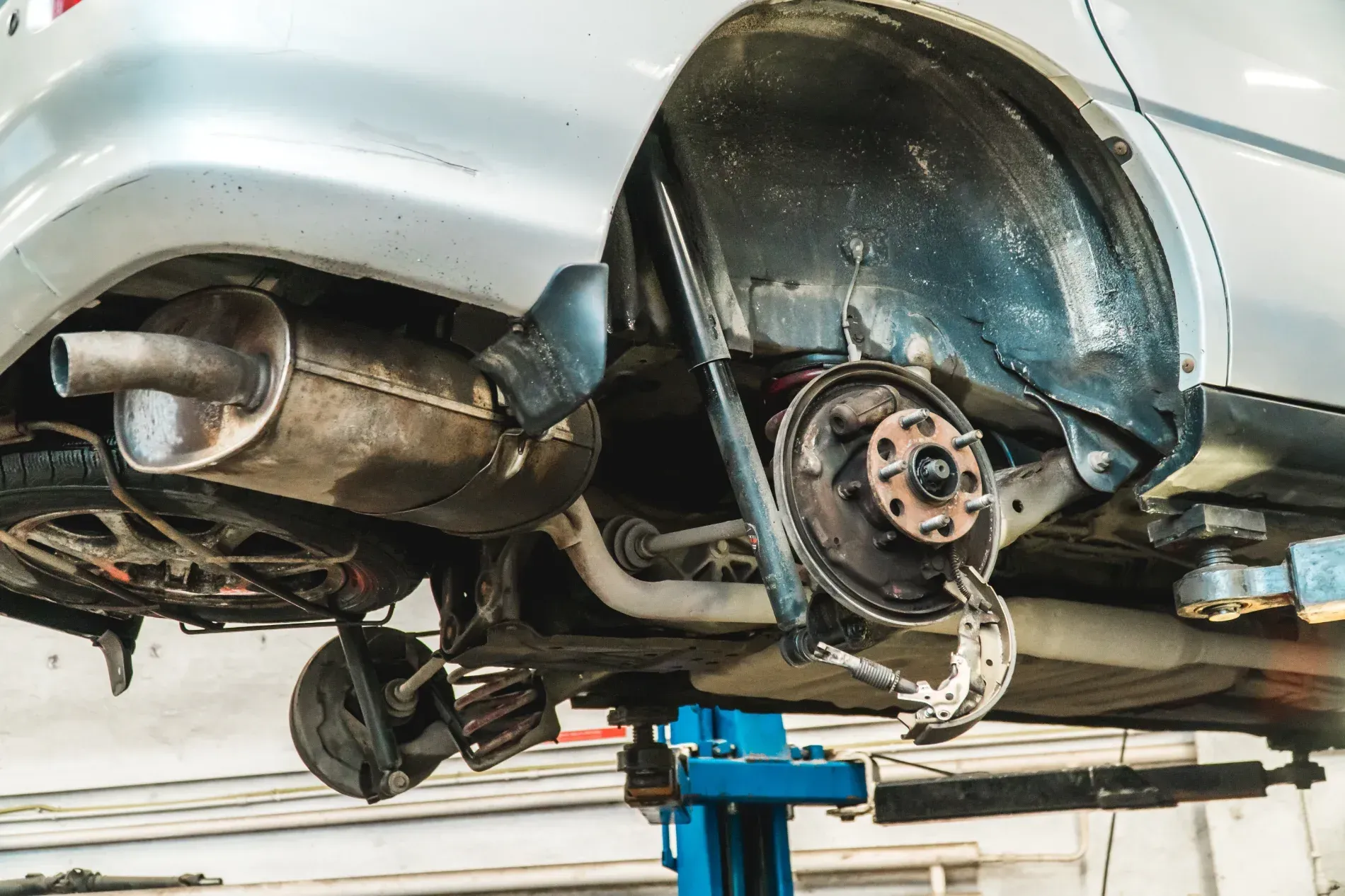A Car Raised On A Hydraulic Lift In A Garage — Kings Brake Service Specialists in Tamworth, NSW
