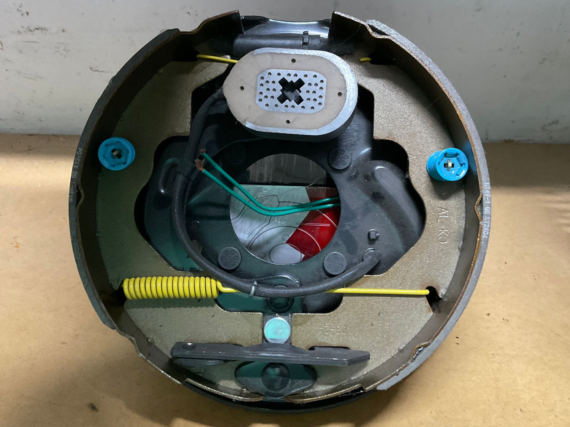 Open circular device with exposed wiring, springs, and a small speaker-like component inside a black housing