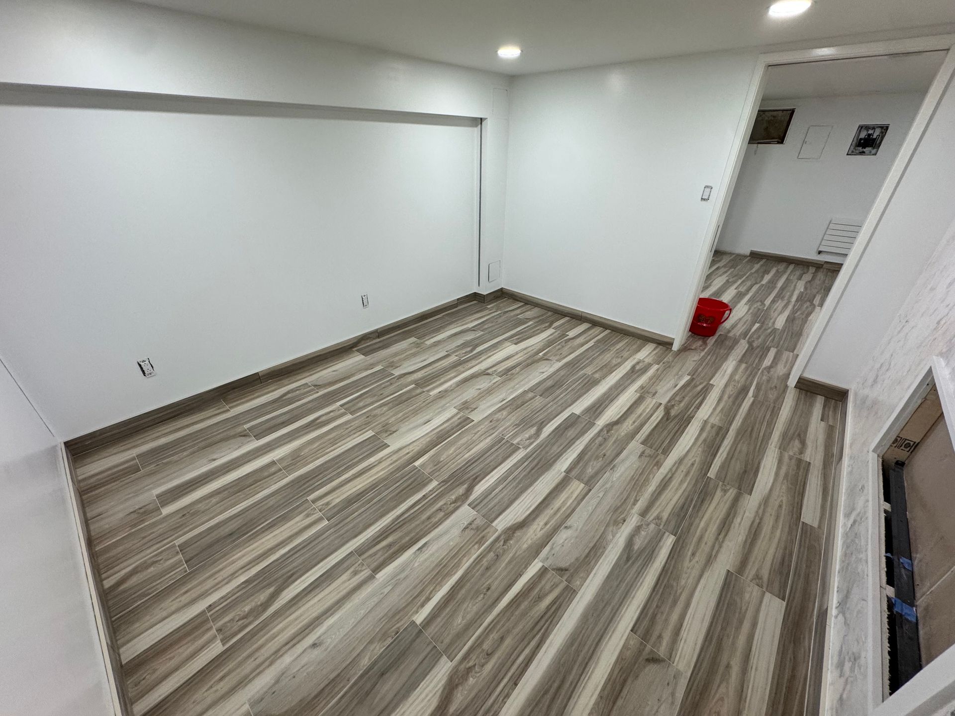 Empty room with wood-look flooring, white walls, recessed lights, and an open doorway.