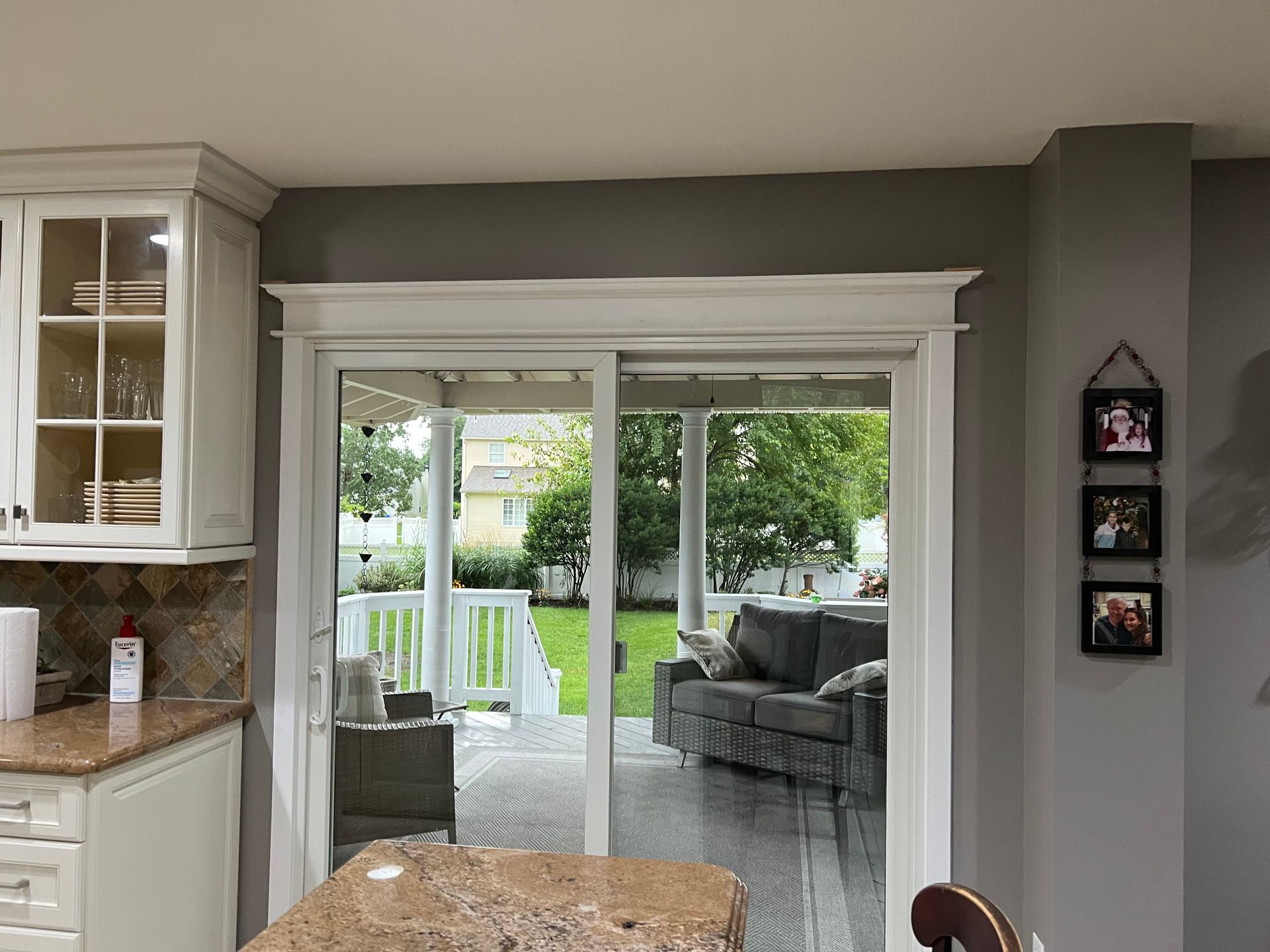 Kitchen sliding doors open to a patio with gray outdoor seating and a green backyard view.