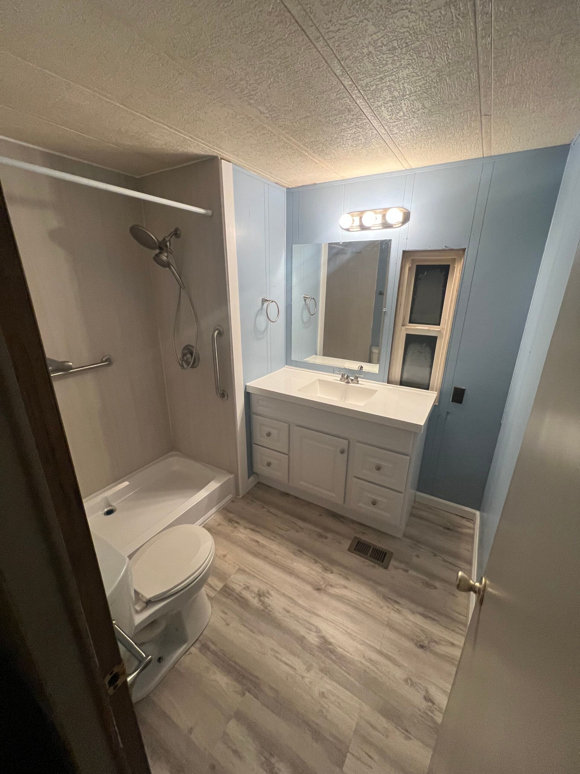 Small bathroom with white tub, sink, toilet, dark floor, and unfinished back wall.