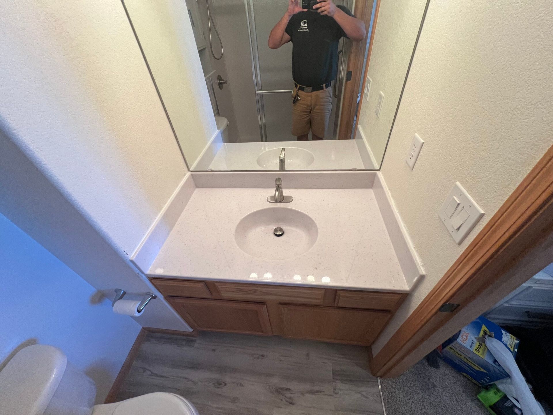 Bathroom vanity with mirror, white sink, and wooden cabinet in a small tiled space.
