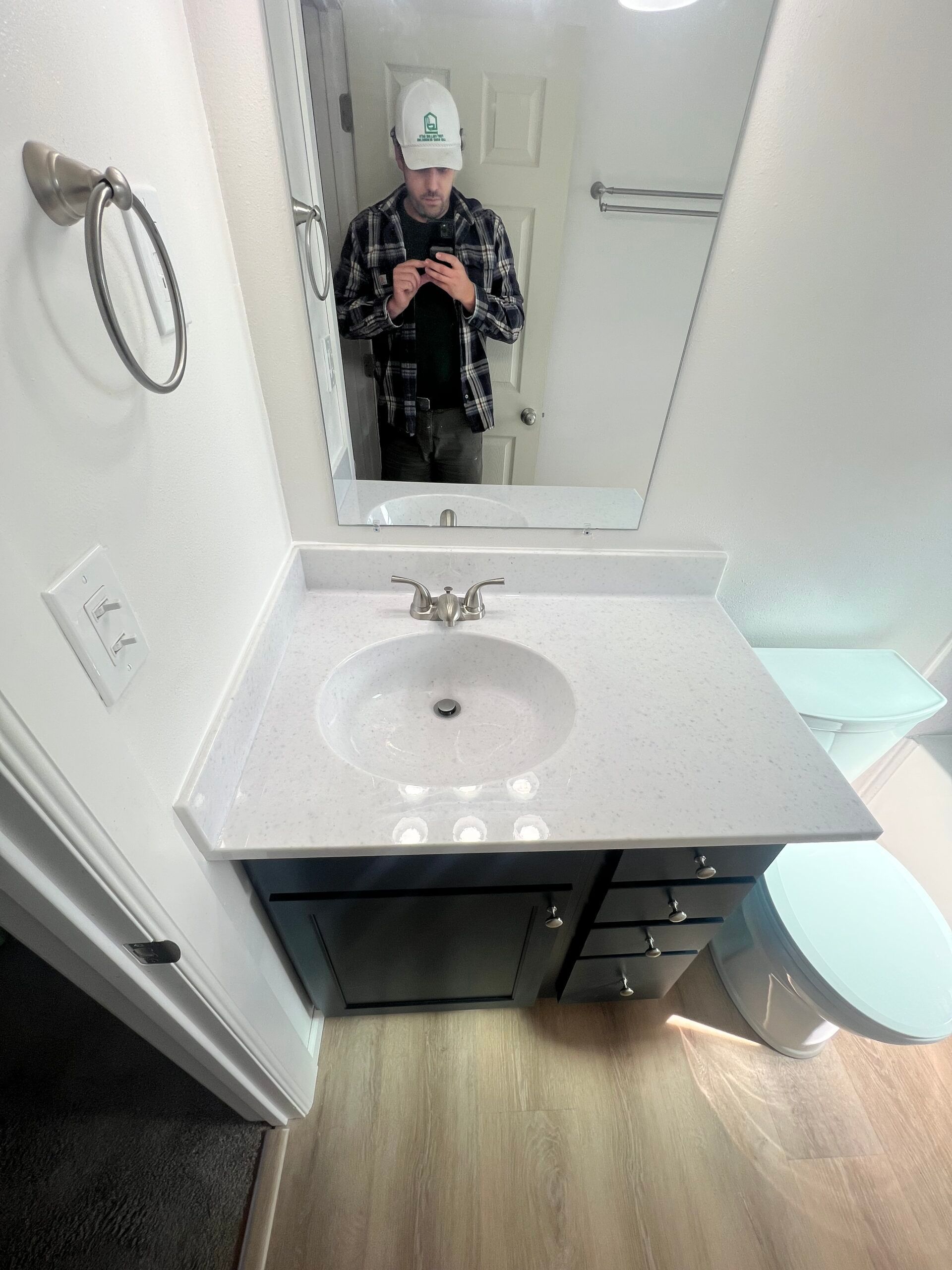 Bathroom vanity with sink and mirror, showing a person taking a mirror selfie.