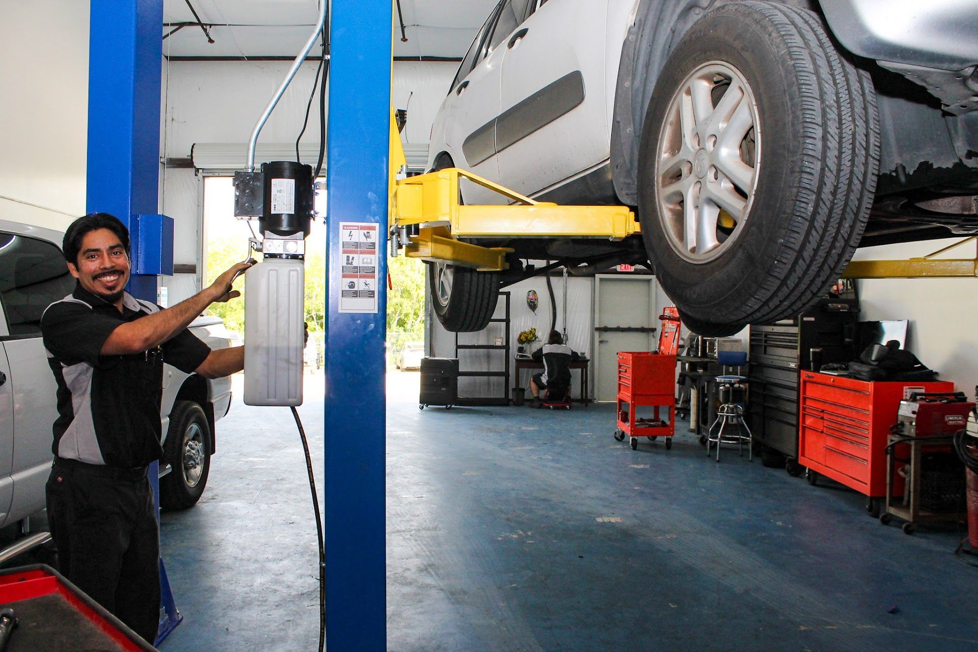 Mechanic Performing Auto Repair Service on Lifted Vehicle | Elite Auto Care