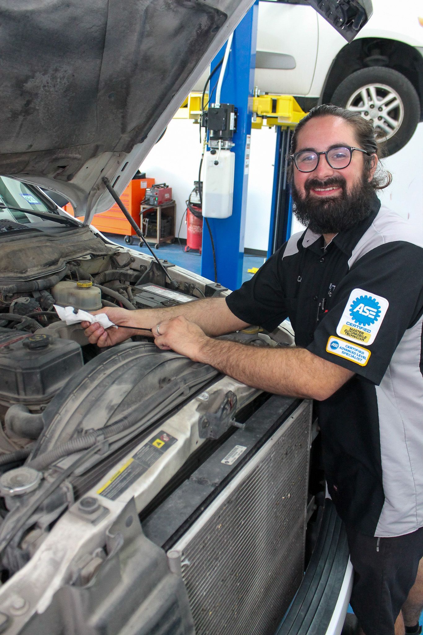 ASE Certified Technician Inspecting Engine Bay During Service | Elite Auto Care