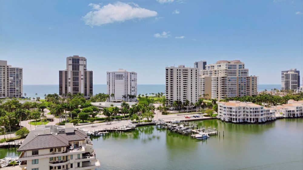 Waterfront marina with boats, high-rise condos, and calm water under a partly cloudy sky