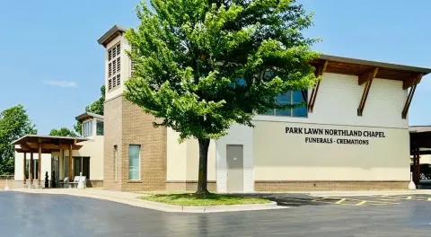 Exterior of  building with tan stone walls and a large tree in front
