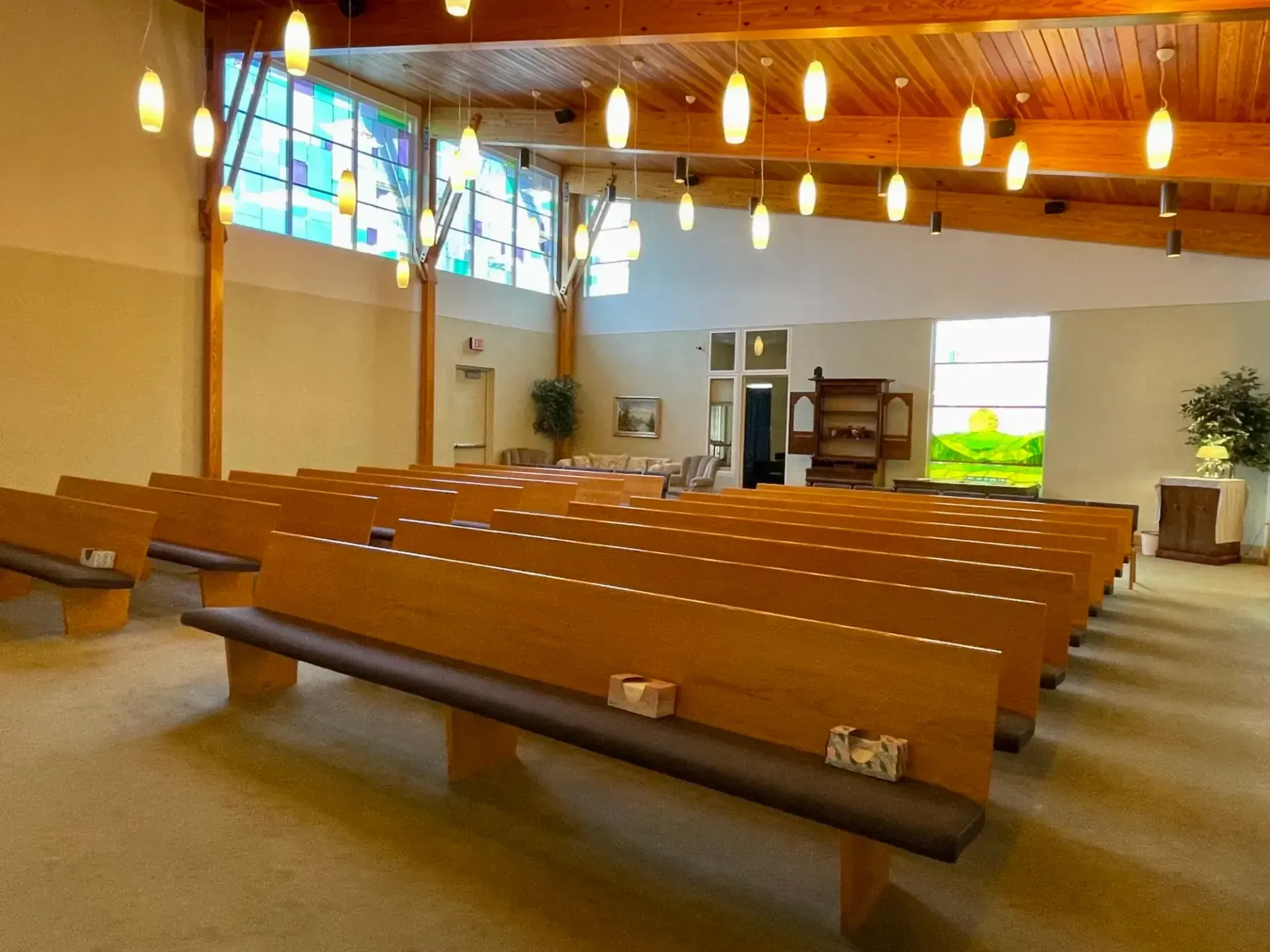 Empty church interior with wooden pews, hanging lights, and stained glass windows