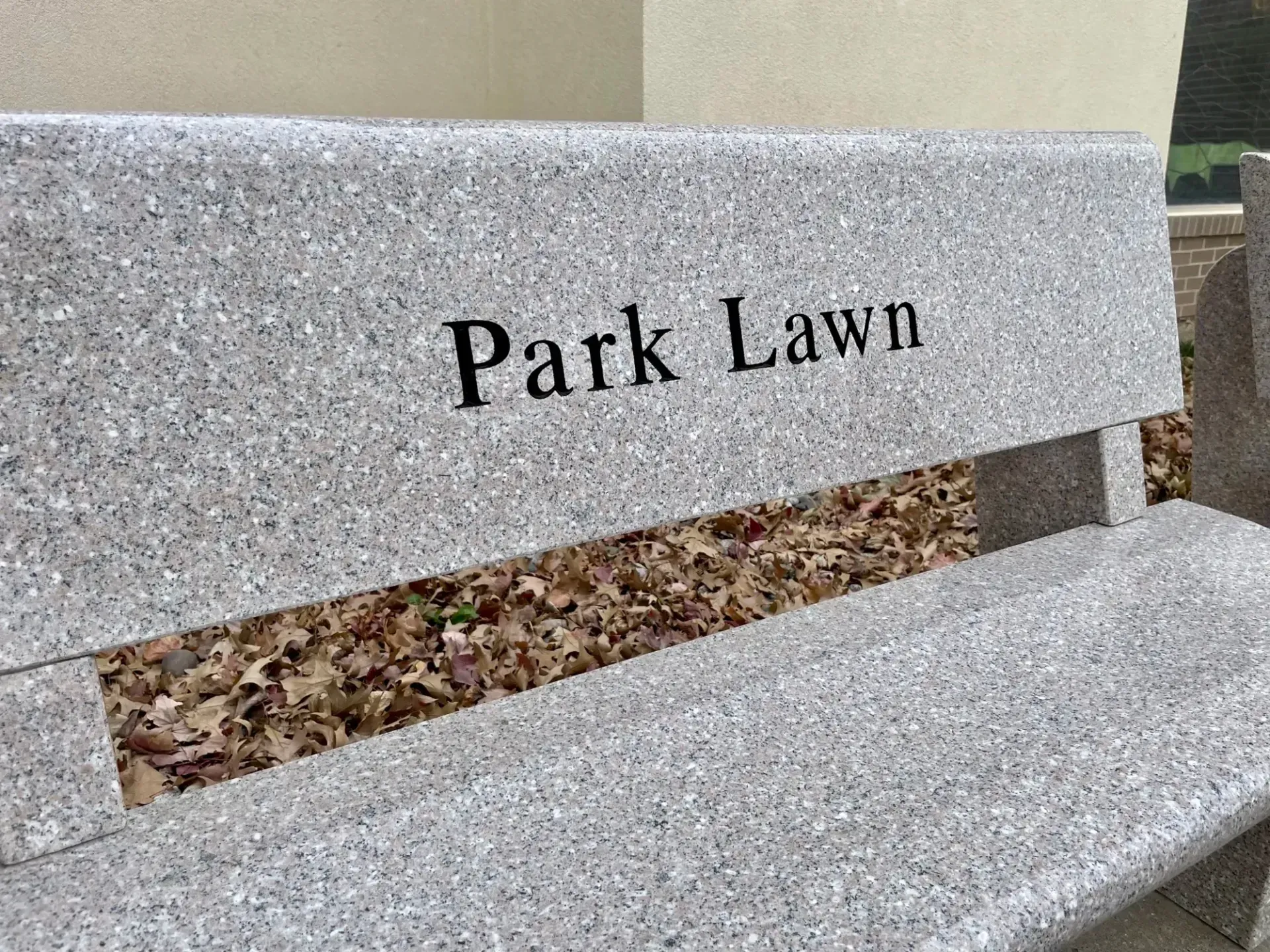 Stone bench with “Park Lawn” engraved on the backrest outdoors