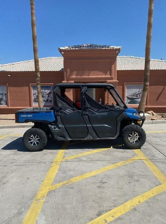 Black utility golf cart parked in a sunny lot in front of a brick building.