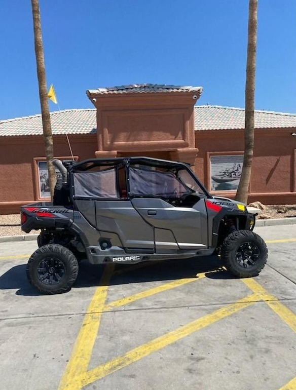 Black off-road side-by-side parked in a marked lot in front of a brick building.