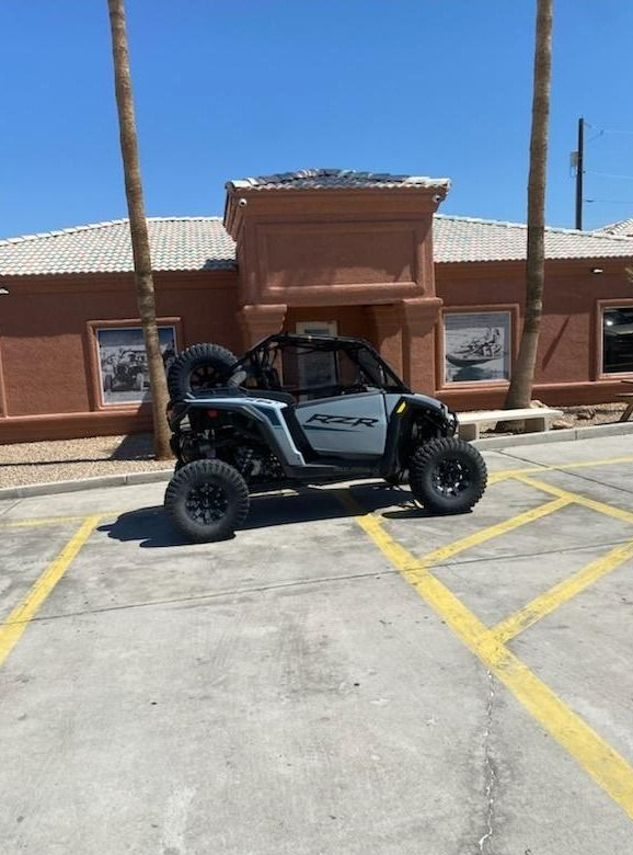 Off-road buggy parked in a sunny lot in front of a brick building.