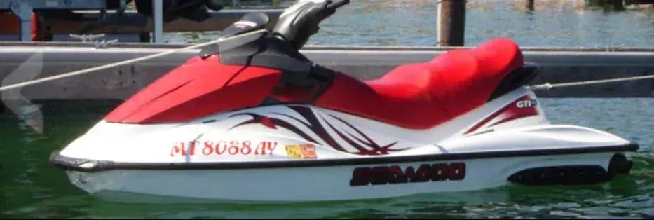 Red and white jet ski floating on calm water beside a dock