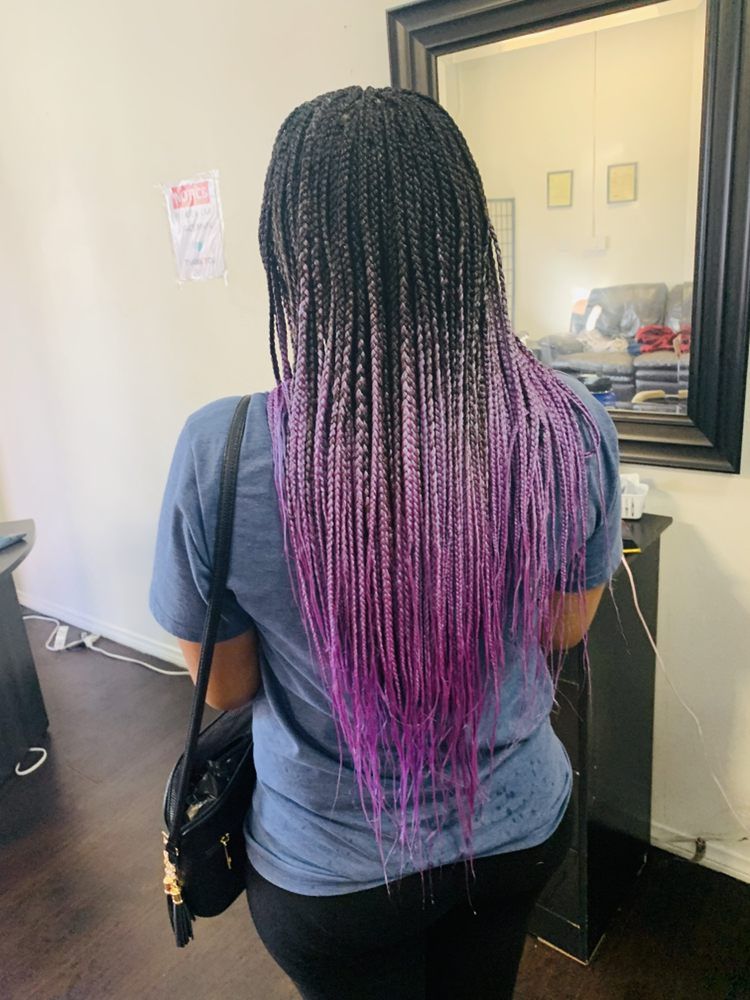 A Woman With Purple Braids Is Standing In Front Of A Mirror
