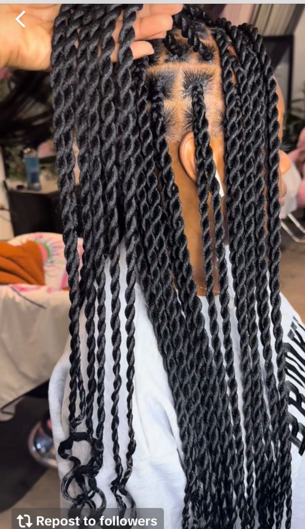 Black twists hairstyle being worked on, indoors.