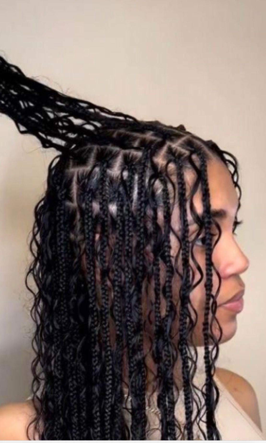 Woman with black box braids and wavy ends, indoors.