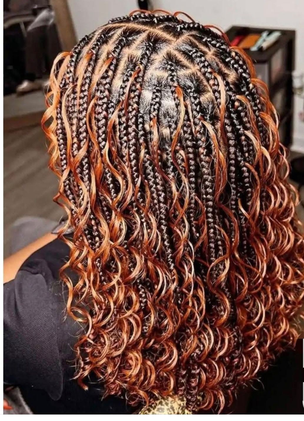 Box braids with auburn curly ends, top view. Braids are dark, sectioned with neat parts.