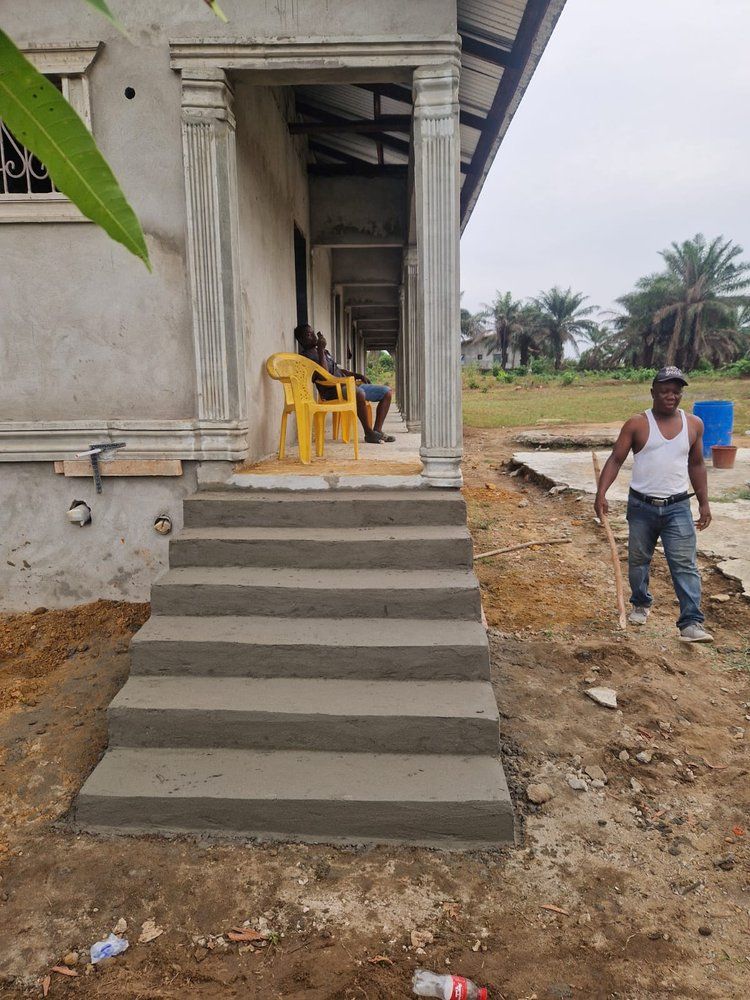 A man is standing in front of a house with concrete steps.