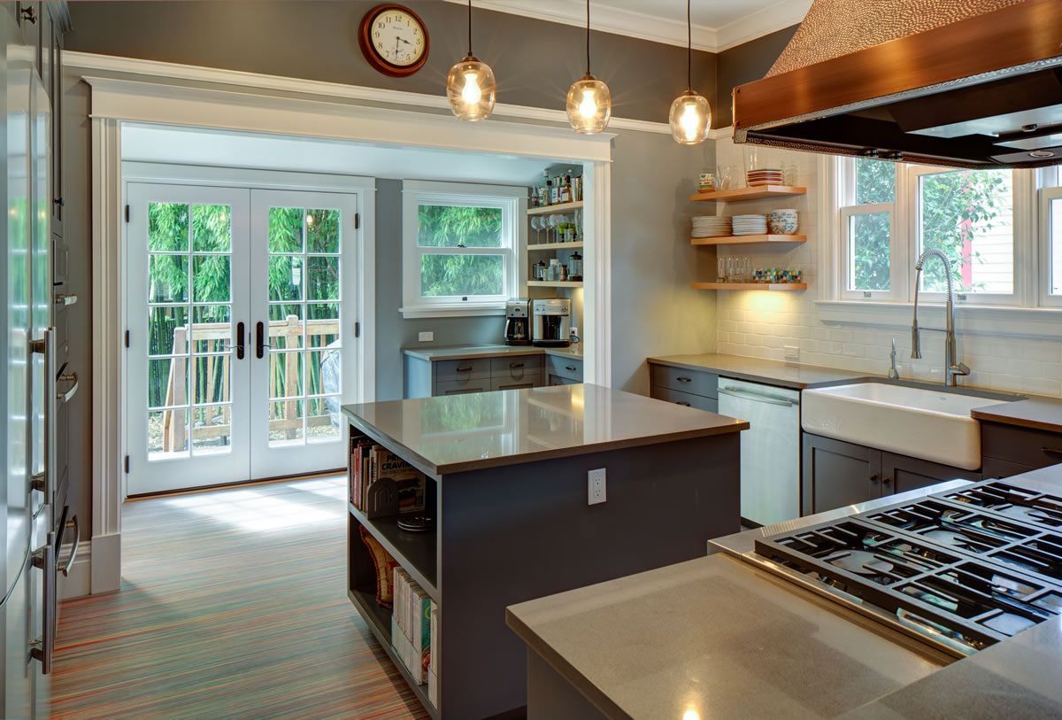 Kitchen with gray cabinets, island, and doors leading to a patio.