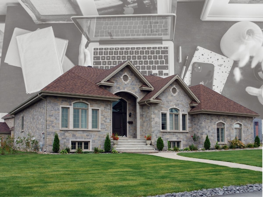 Stone suburban house with red roof and green lawn, with laptop, papers, and coffee cup in the background