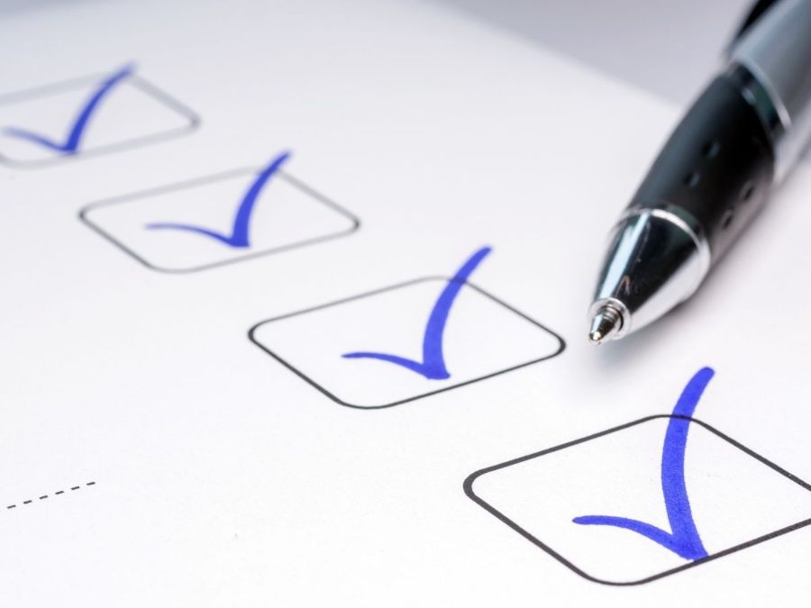 Checklist with blue check marks and a pen poised over the paper