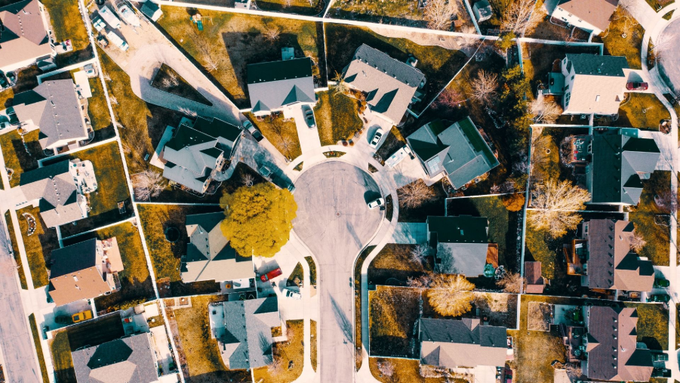 Aerial view of a suburban cul-de-sac with houses, trees, and parked cars in fall colors
