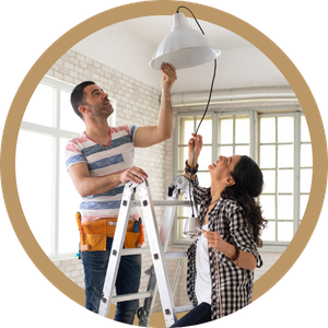 Two people on ladders installing a ceiling light in a bright room