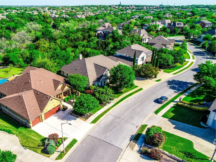 Aerial view of a suburban neighborhood with curved streets, houses, trees, and green lawns