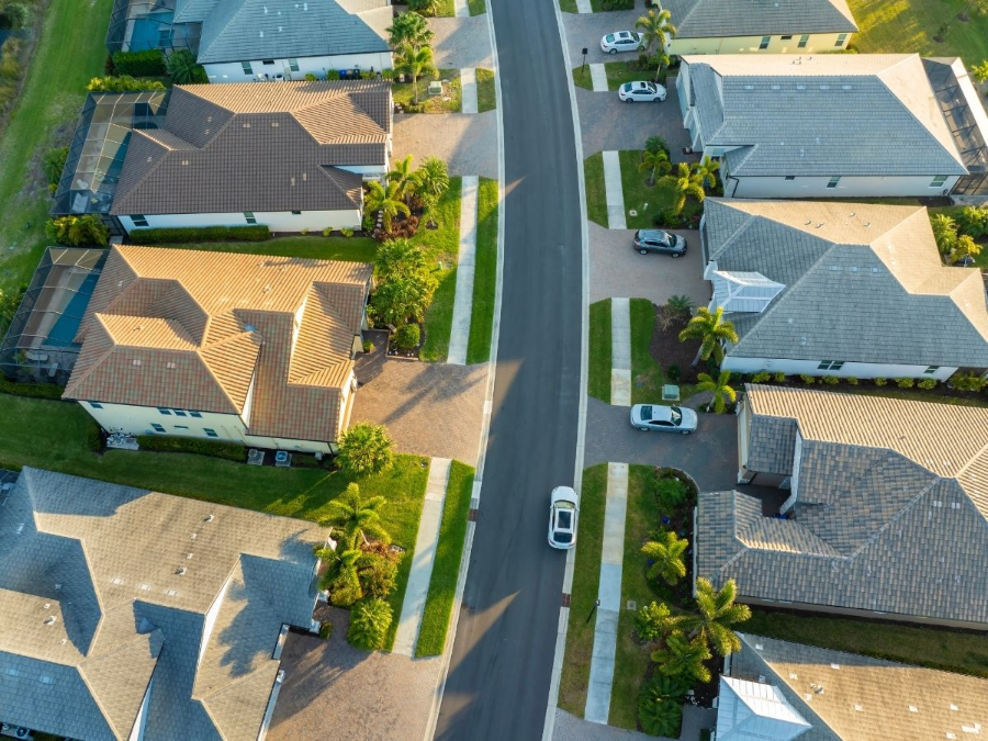 Aerial view of suburban homes lining a curved street with parked cars and green lawns