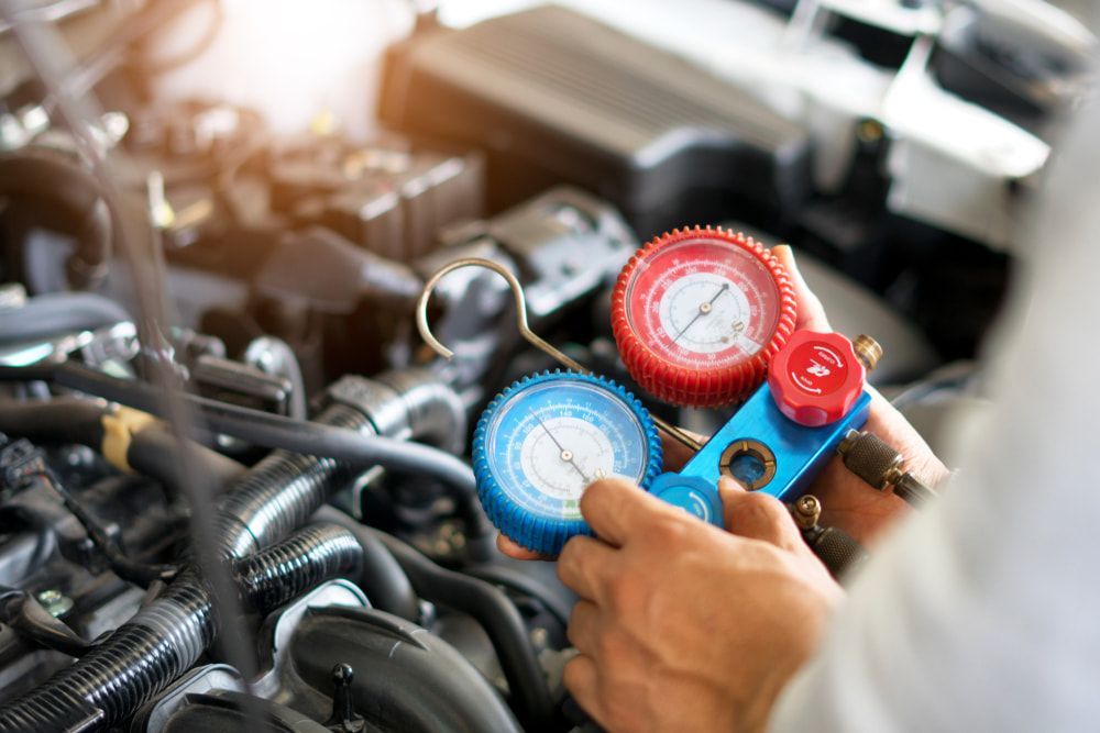 A Close Up of a Person Holding a Gauge in Front of a Car Engine — Brittle's Family Auto Centre in Moffat Beach, QLD