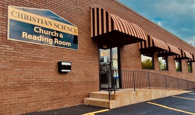 A brick building with a sign that says christian science church & reading room
