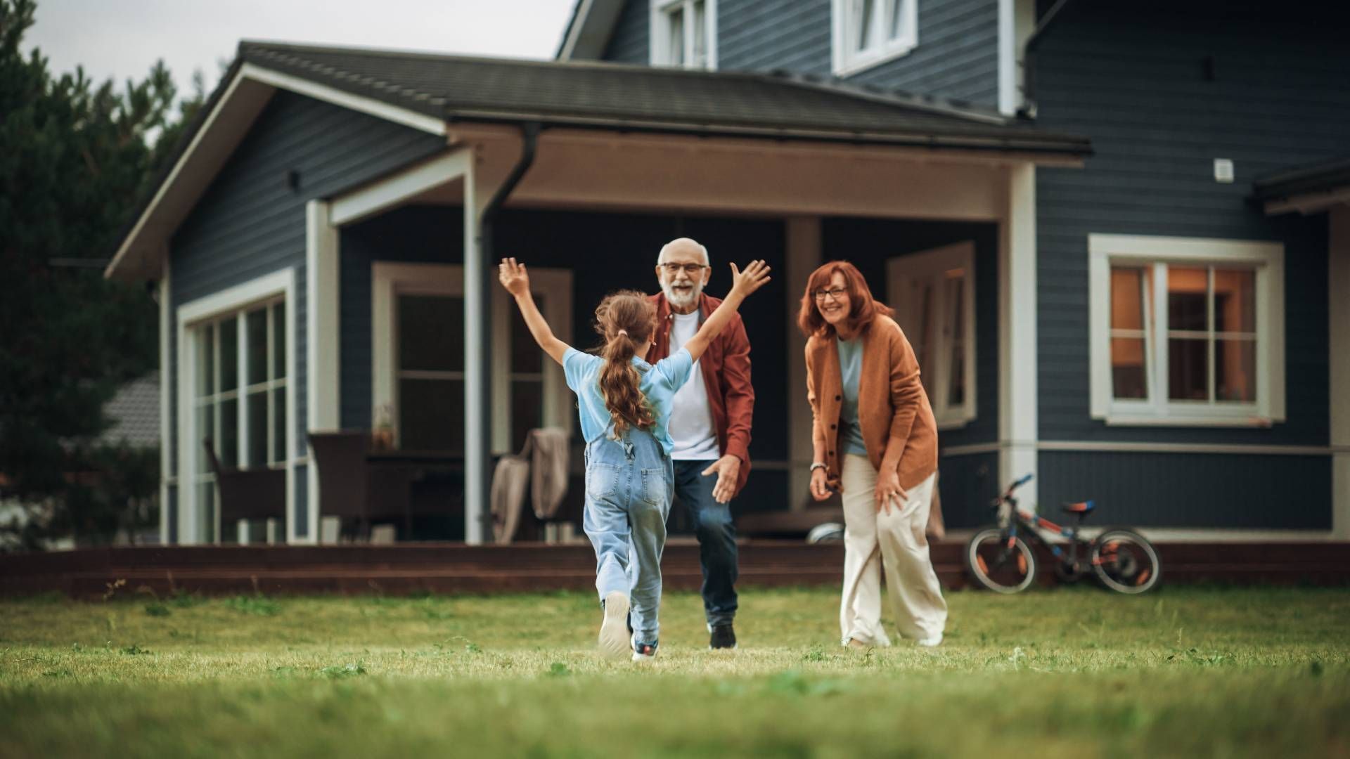 Grandparents greeting their grandchild in front of their home