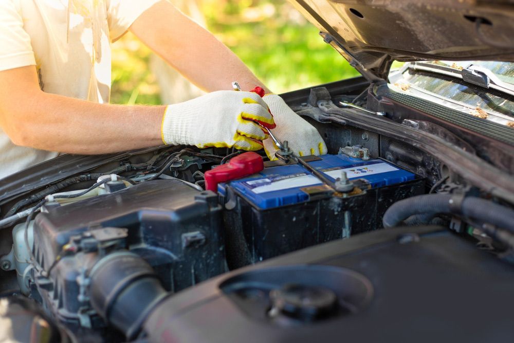 A man unscrews a car battery mount — A Grade Oils & Batteries In Benalla VIC