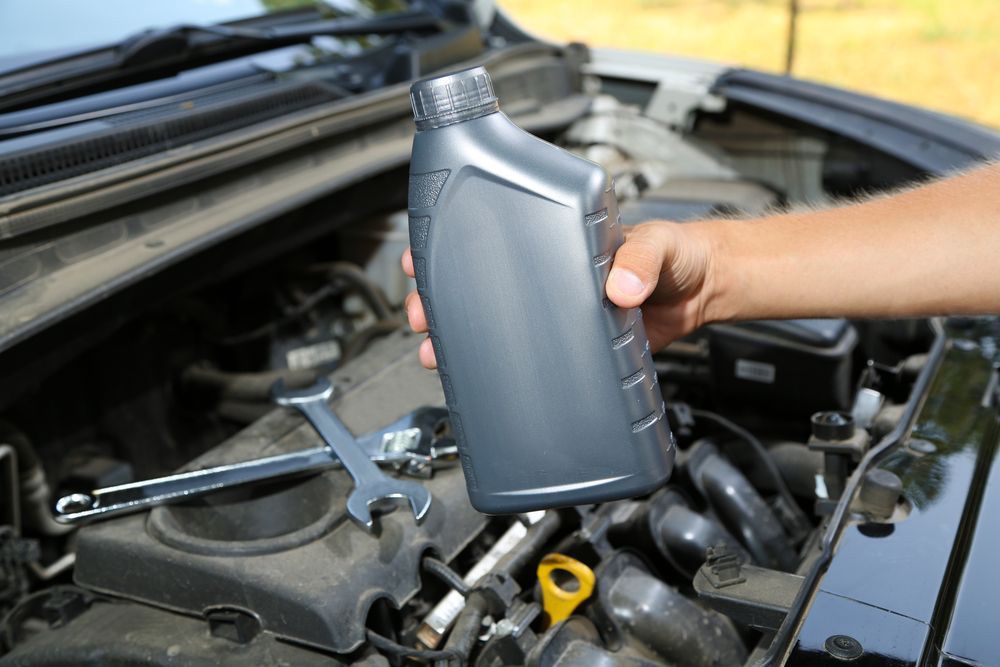 Auto mechanic hand holding motor oil — A Grade Oils & Batteries In Wangaratta VIC