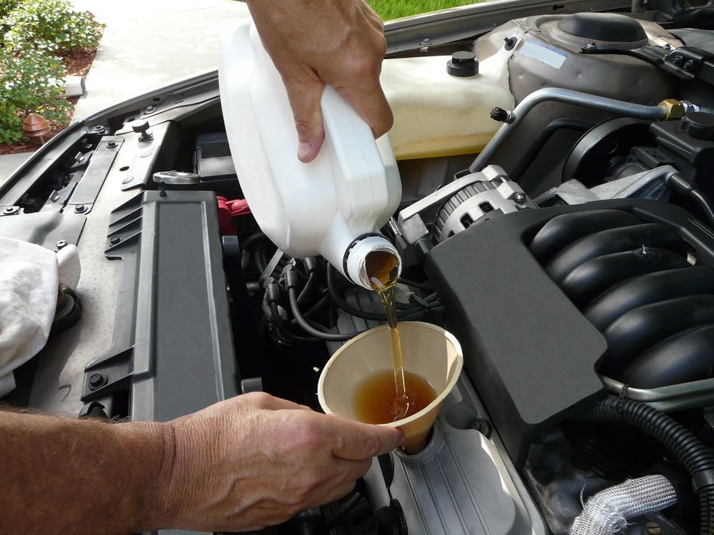 Male adding oil with a funnel — A Grade Oils & Batteries In Wangaratta VIC