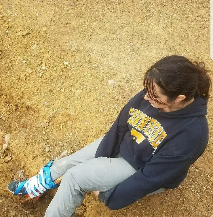A woman wearing a sweatshirt that says virginia sits on the ground