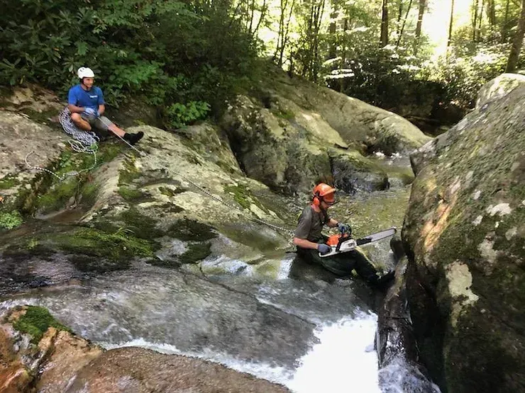 A man is sitting on a rock next to a waterfall.