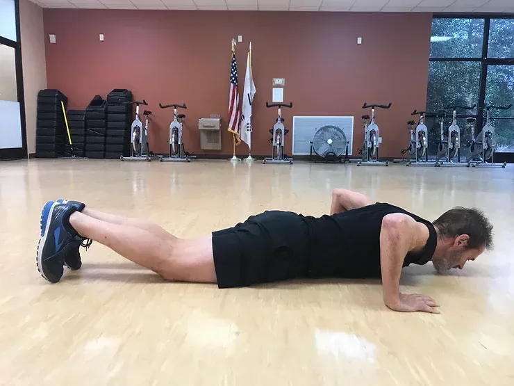 A man is doing push ups in a gym.