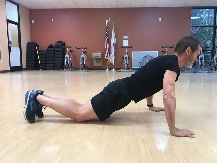 A man is doing push ups on the floor in a gym.