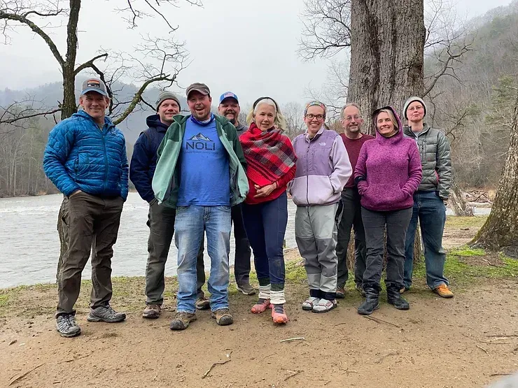 A group of people are posing for a picture in front of a river.