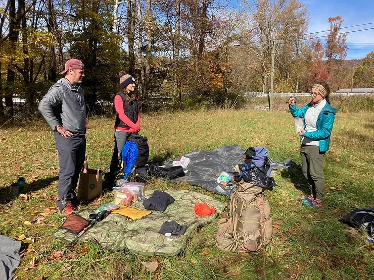 A group of people are standing in a field talking to each other.
