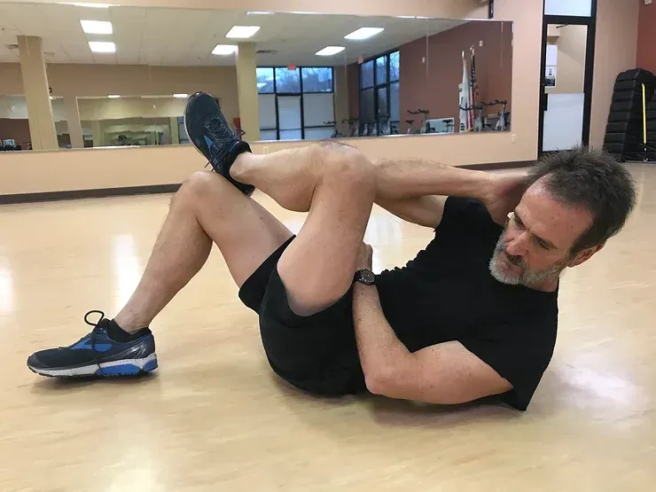 A man is doing a crunch on the floor in a gym.