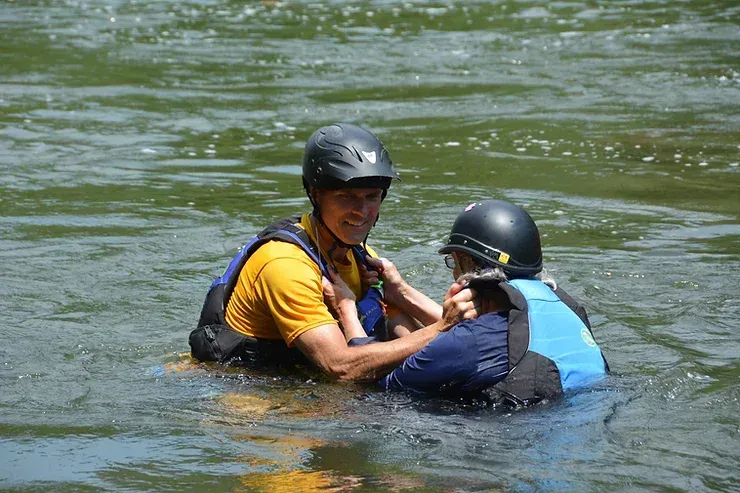 A man is helping another man out of the water.