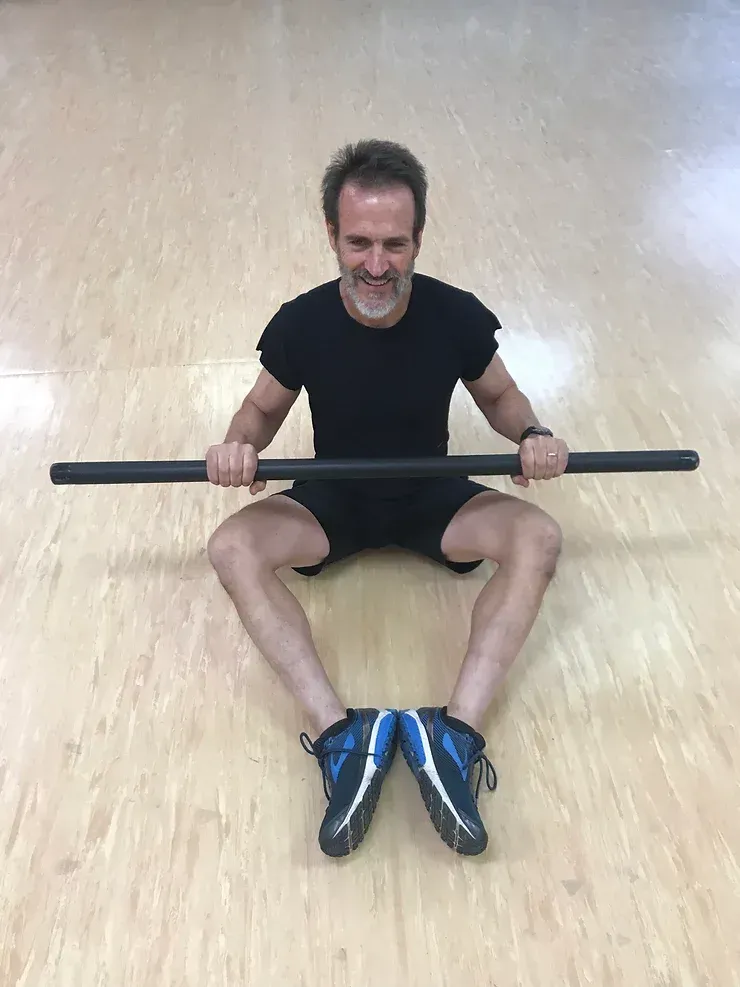 A man is sitting on the floor holding a barbell.