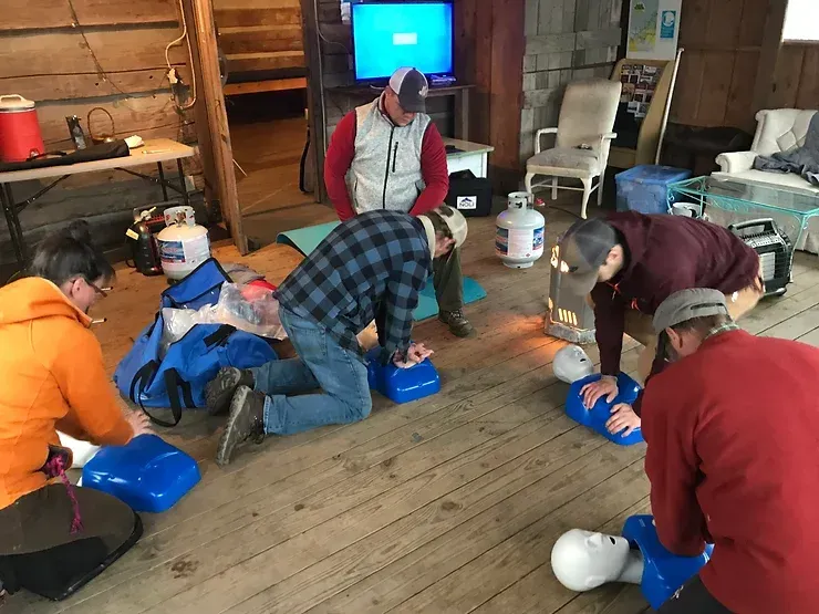A group of people are practicing a cpr on a mannequin.
