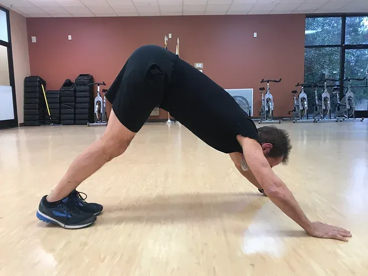 A man is doing a downward dog exercise in a gym.