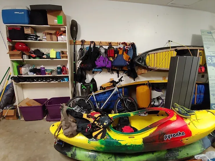 Two kayaks are stacked on top of each other in a garage.