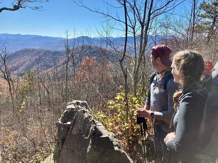 A man and a woman are standing on top of a mountain looking at the mountains.