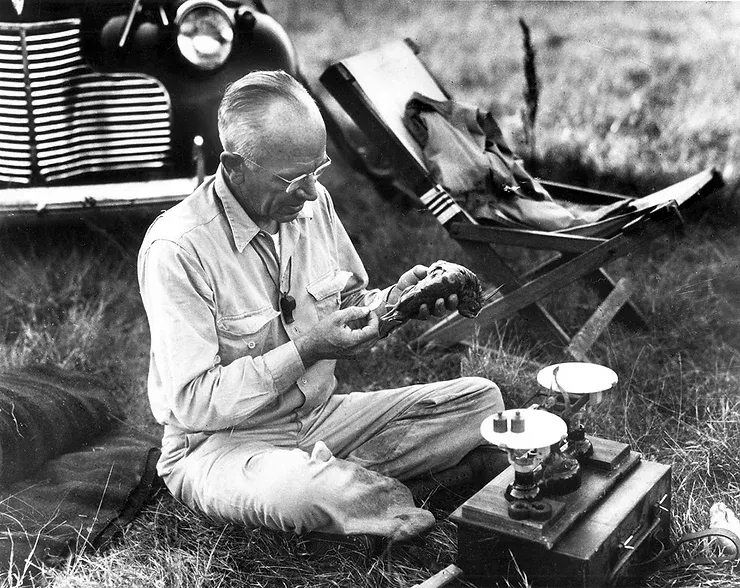 A black and white photo of a man sitting in the grass